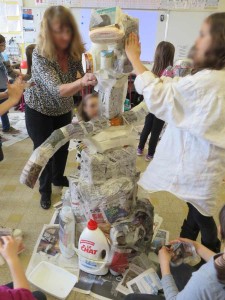 Les enfants recouvrent leur sculpture de papier journal
