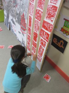 Une petite fille colle les hanku sur la fresque