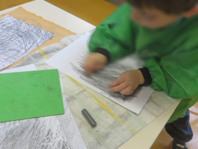 Un enfant frotte de la mine de crayon à papier sur une feuille