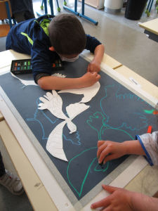 Un enfant s'applique à dessiner un oiseau