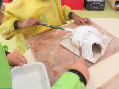 Les enfants peignent leur igloo en blanc