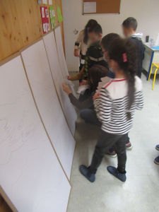 Les enfants collent leurs dessins sur la fresque