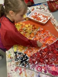 Fillette qui colle des petits objets sur le tableau