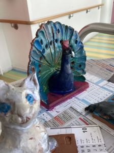 Figurine de chat devant un paon