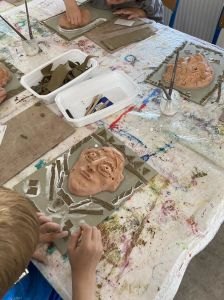 Les enfants décorent leur tableau avec de l'argile crue